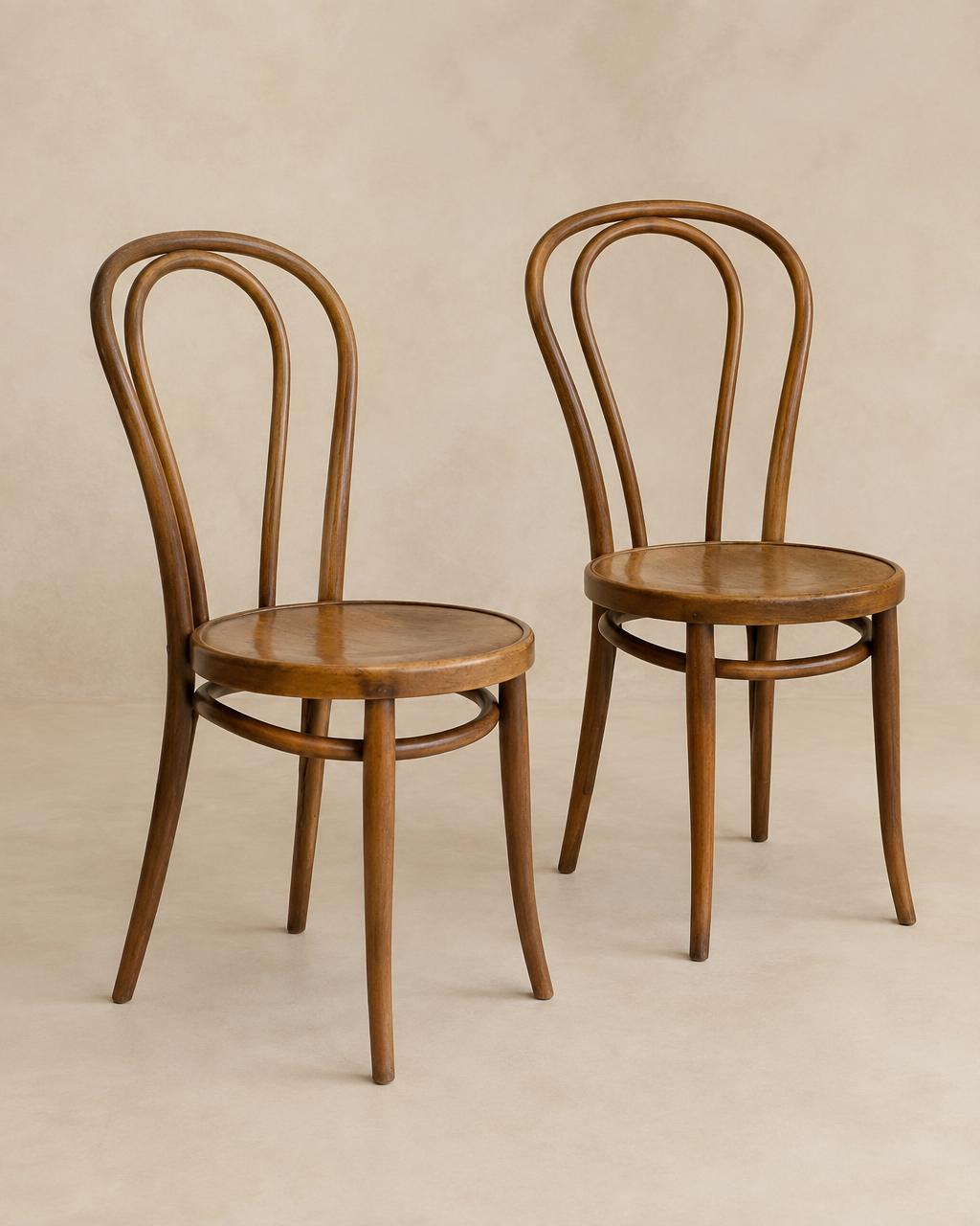 Two honey-toned antique bentwood café chairs