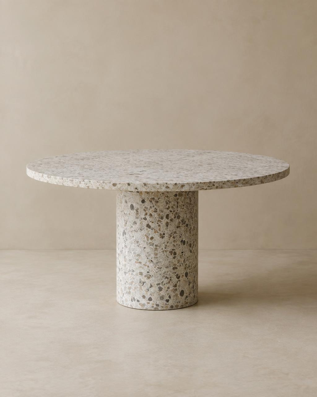 Round pale terrazzo dining table on cylindrical pedestal
